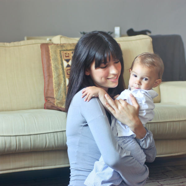 une jeune femme assise en fasse d'un meuble avec un bébé dans ses bras